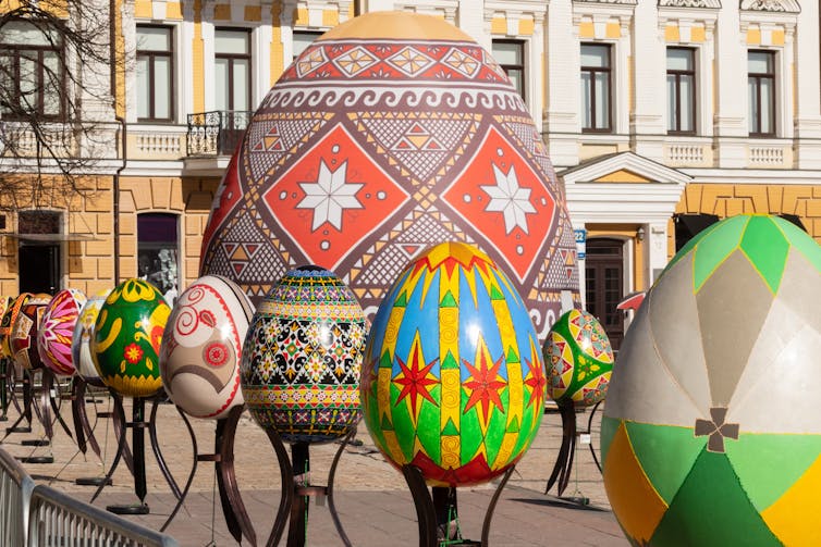 Artists display painted multicolored Easter eggs against the background of a historic building