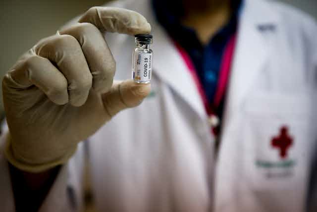 A medic holding up a vial of COVID vaccine.