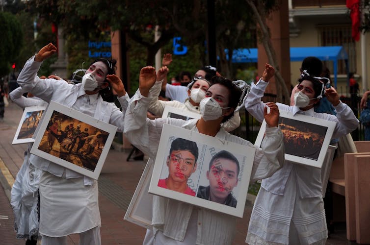 Women in white, carrying pictures of the protest marches where two young men were killed