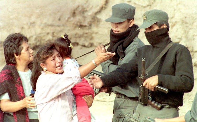 Peruvian police speak with a crying woman holding a baby