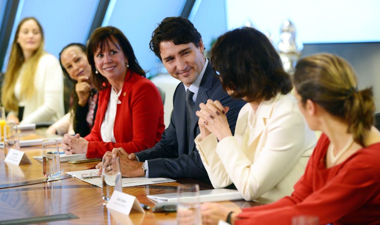 Justin Trudeau sits on a panel with women.