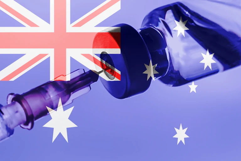 A vaccine vial with an Australian flag in the background.