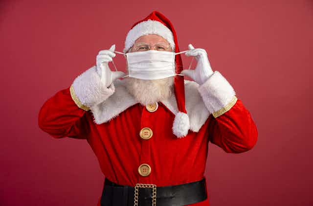 Santa putting a surgical mask on.