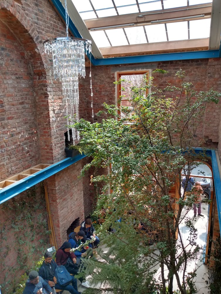 Gutted out interior of a terraced house, decorated with trees and a chandelier.