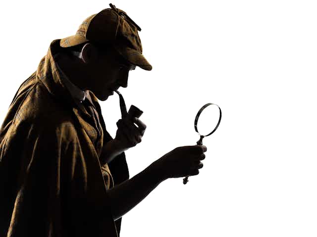 Silhouette of man with deerstalker hat, pipe and magnifying glass.