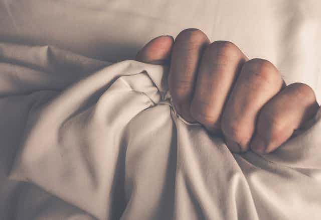 Woman's hand clutching sheet