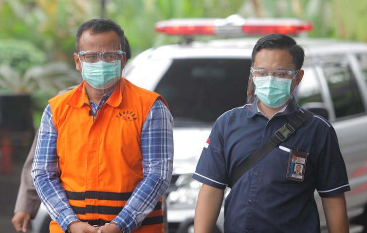 Menteri KKP Edhy Prabowo memakai jaket oranye ditemani salah seorang petugas KPK.