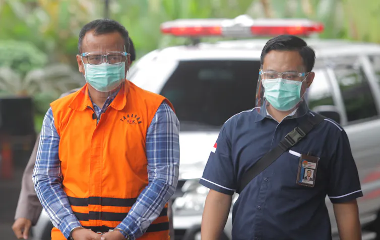 Menteri KKP Edhy Prabowo memakai jaket oranye ditemani salah seorang petugas KPK.