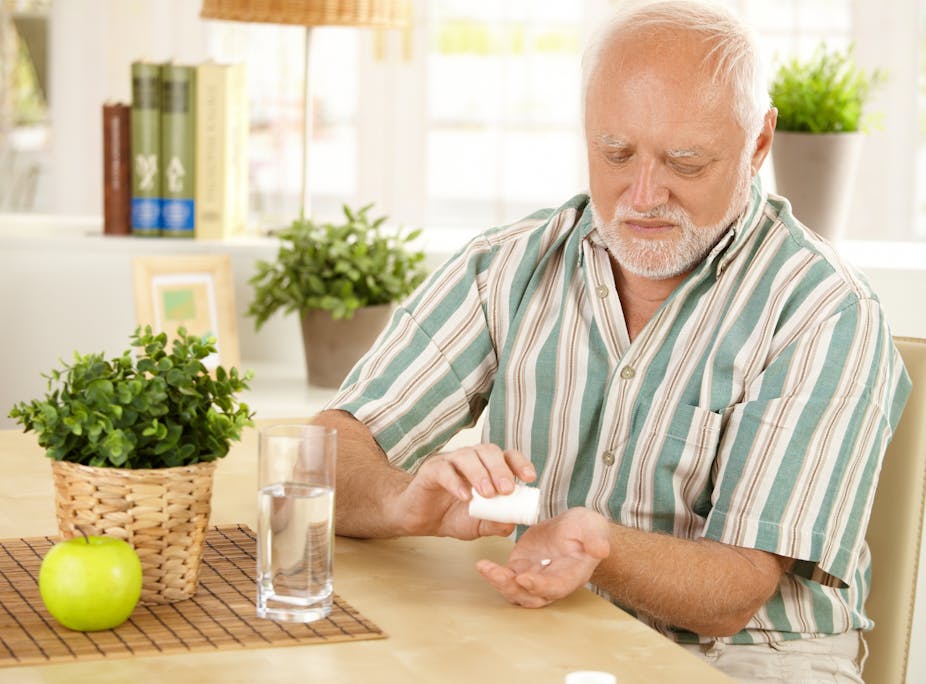 A man taking medication tablets with water