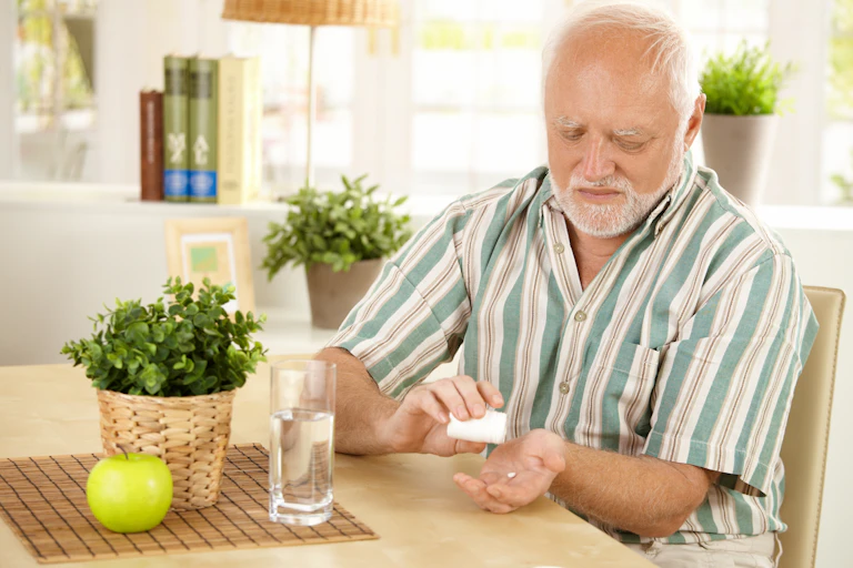 A man taking medication tablets with water