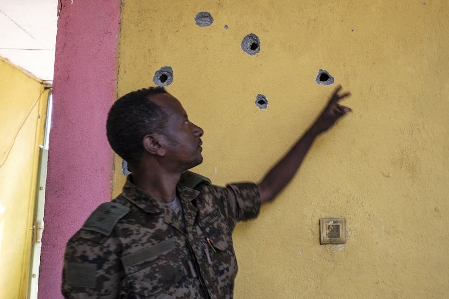 Un soldat montre des impacts de balles sur un mur