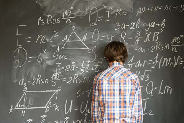 Boy in front of blackboard with complicated maths