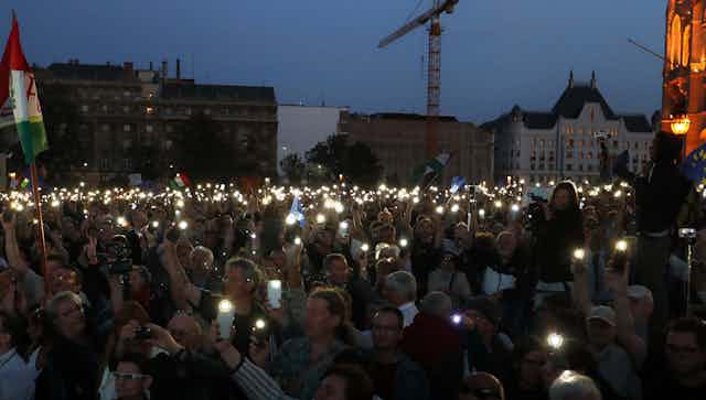 A crowd of white people holding candles in the dark.