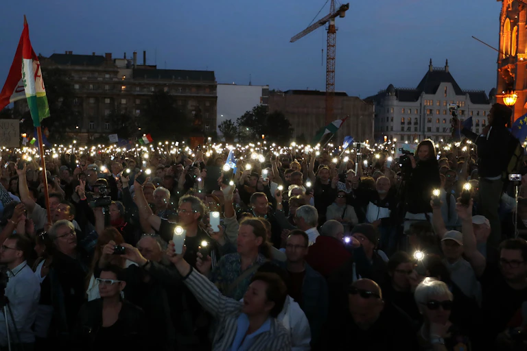A crowd of white people holding candles in the dark.