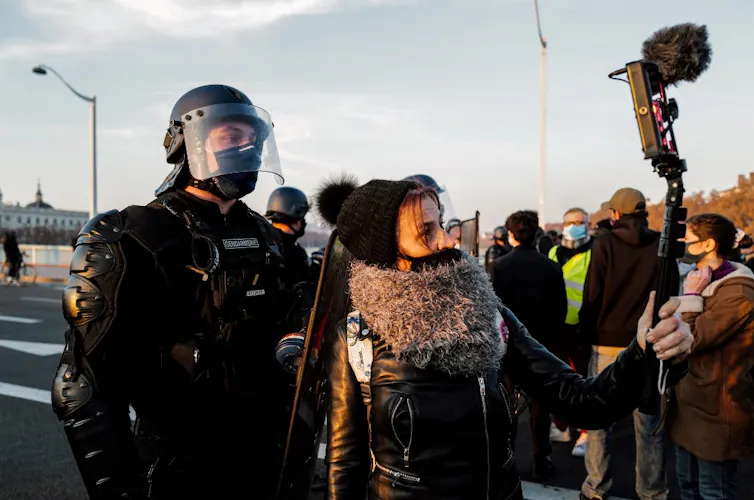 Une femme filme un garde mobile lors de la manifestation pour la Marche des libertés du 27 novembre à Paris