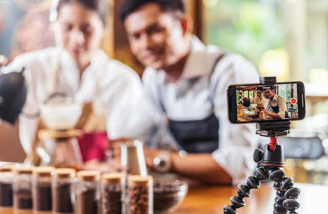 Man and woman record themselves making coffee on a smartphone.
