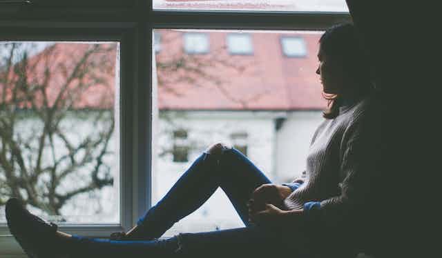 A woman sits staring out a window.