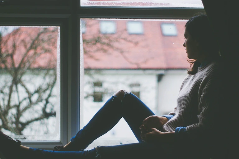 A woman sits staring out a window.