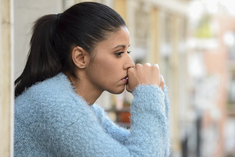 A woman looks worriedly into the distance.