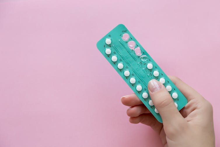 A woman holds a packet of contraceptive pills.
