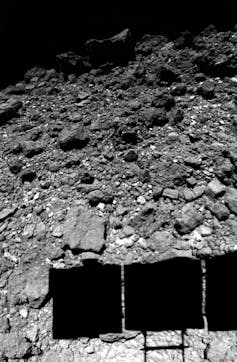 The surface of asteroid Ryugu, as observed by the Hayabusa2 spacecraft just before  landing. The spacecraft’s solar panels cast a shadow on the surface.