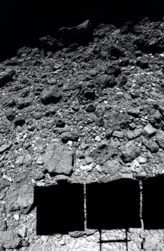 The surface of asteroid Ryugu, as observed by the Hayabusa2 spacecraft just before landing. The spacecraft’s solar panels cast a shadow on the surface.