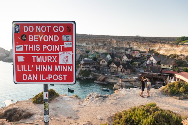 Tourists walking beyond a 'do not go beyond this point' sign.