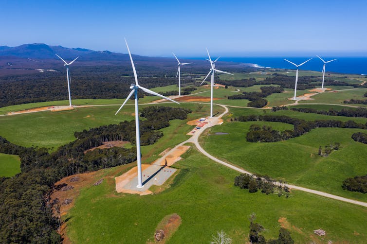 Aerial view of win turbines over a green field.