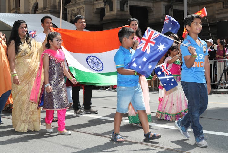 Family waves Indian and Australian flags in an Australia Day parade.