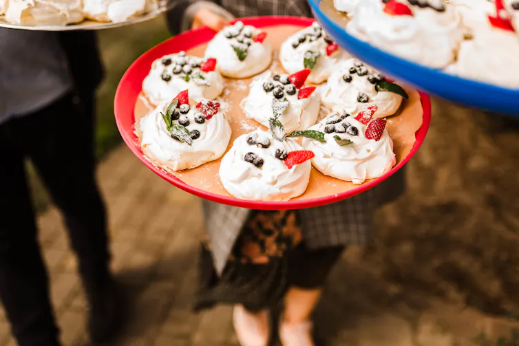 A plate of mini tropical fruit pavlovas with berries