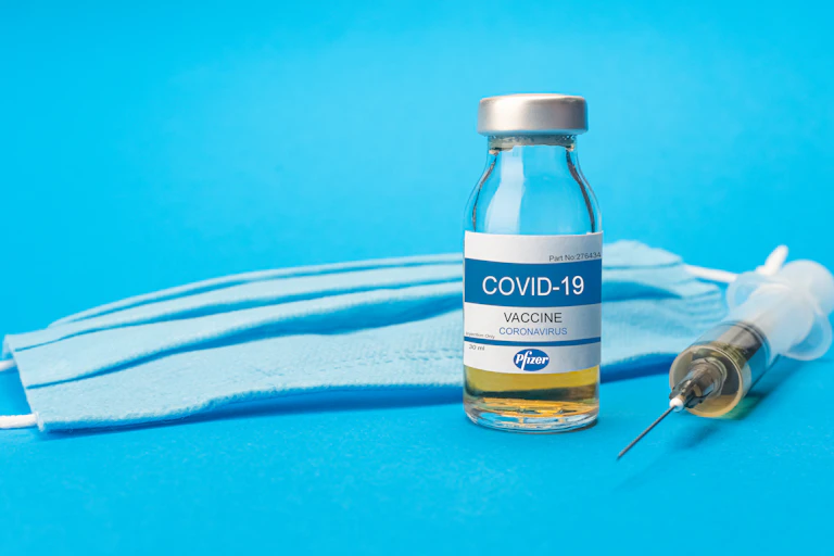 Bote con vacuna de Pfizer, jeringuilla y mascarilla