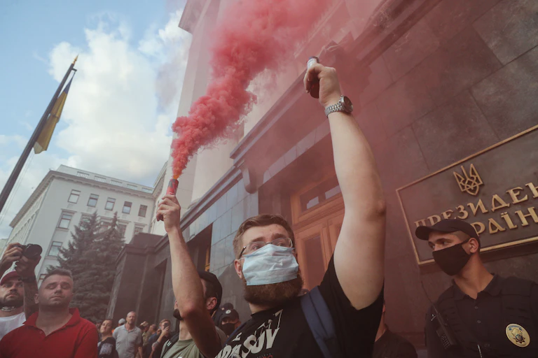 A man in a medical mask holds a red flare in protest at the ceasefire in eastern Ukraine.