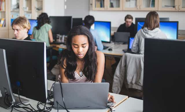 An African American girl uses a computer in class. 