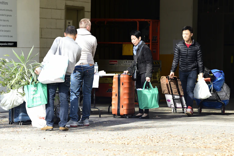 Evacuated residents leave the Mascot Towers apartments with their belongings