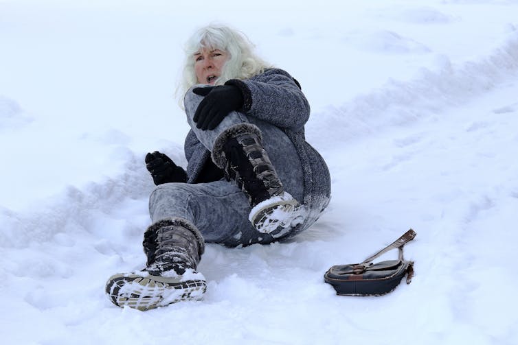 A woman lies on snowy ground after slipping.