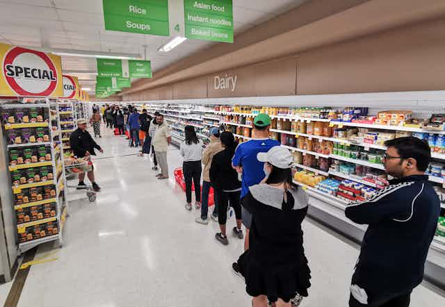 Shoppers lined up in a supermarket aisle