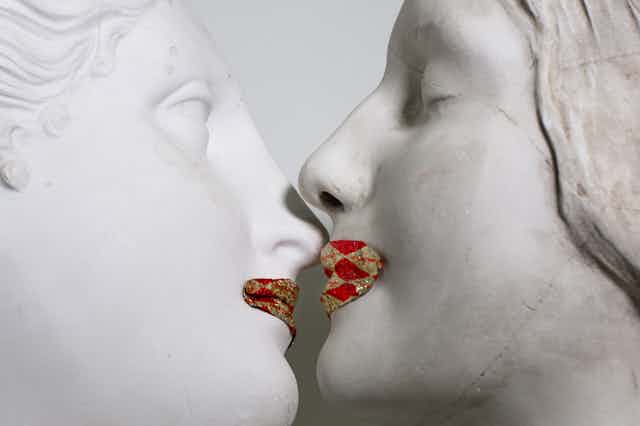 Sculptures with gold and red painted lips embrace