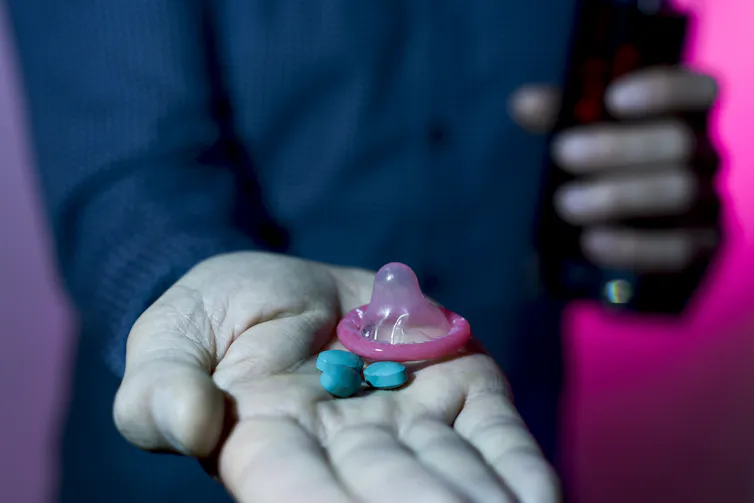 white hand holding drugs and condom