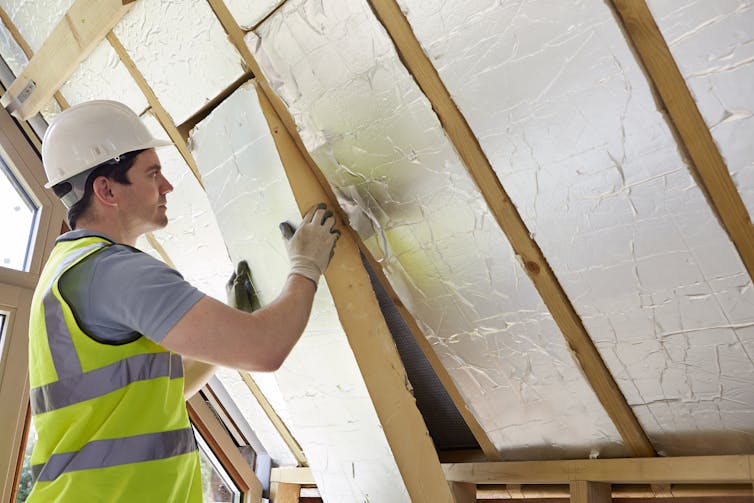 A builder installs insulating boards into the roof of a house.