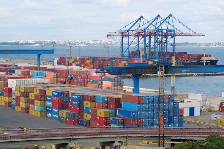 Colourful shipping containers and cranes fill a bustling seaport.