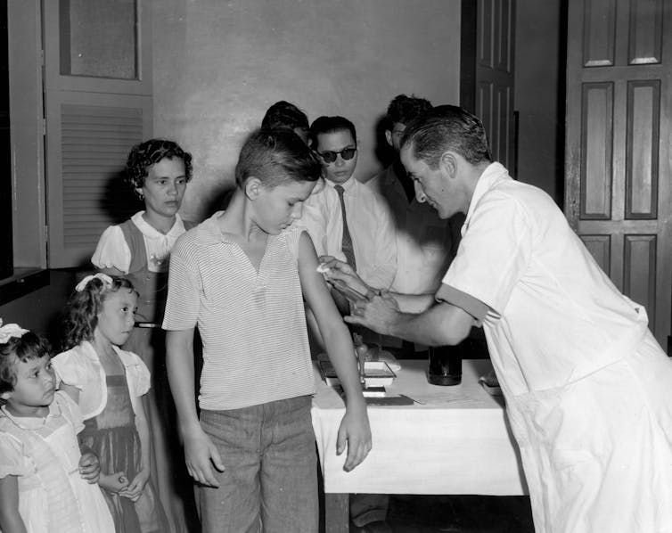 Black and white photo of a doctor injecting a child in the arm