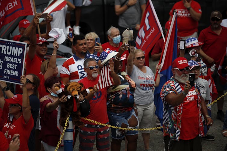 Maskless Trump supporters are seen in a crowd.