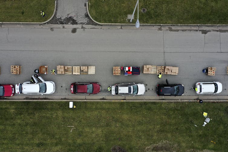 Volunteers load boxes of food into a line of waiting cars.