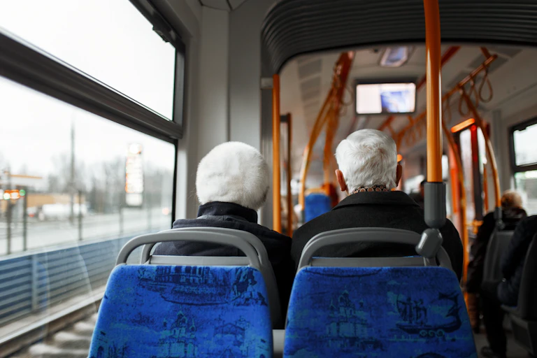The back of the heads of two elderly passengers seated on a bus