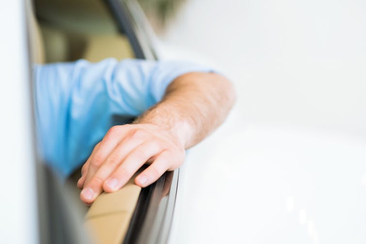 A person driving a car with their arm out the window