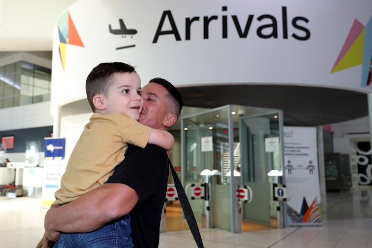 A man embraces a young boy at the arrivals hall in Perth airport.