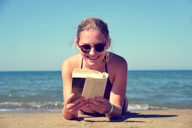 Girl reading a book on the beach.