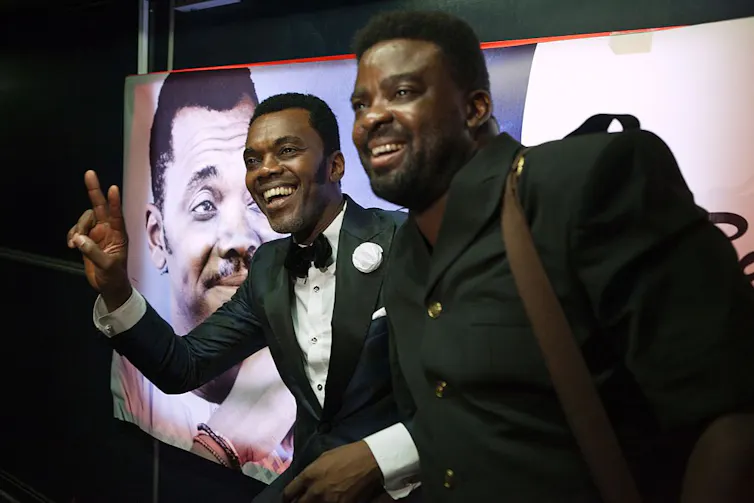 Two men smiling and waving.
