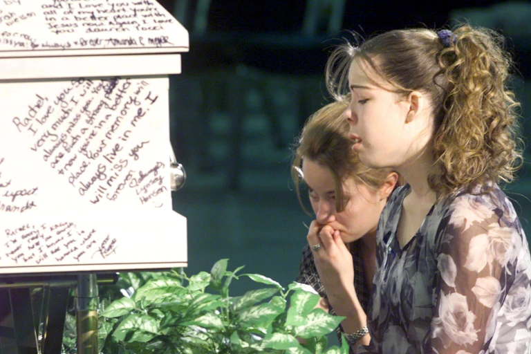 Two young women cry after writing messages on their friend's coffin after a mass shooting in Columbine High School, Littleton, Colorado.