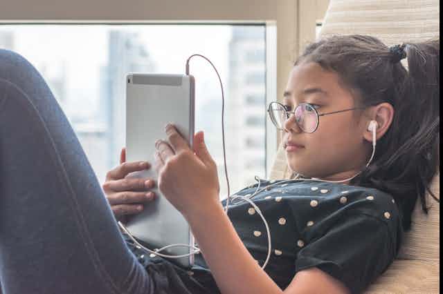 Girl looking at tablet with headphones in
